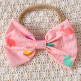 Pink baby bow hair accessory with colorful rabbits.