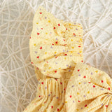 Yellow baby girl suit with colorful heart patterns.
