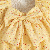 Yellow baby girl suit with a large bow and small heart patterns on.
