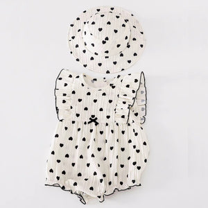 White baby romper with black heart patterns and matching hat.