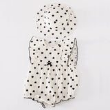 White baby romper with black heart patterns and matching hat.
